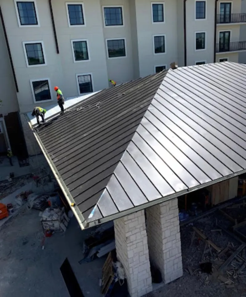 Crew installing standing seam metal roof panels on a commercial project in Amityville